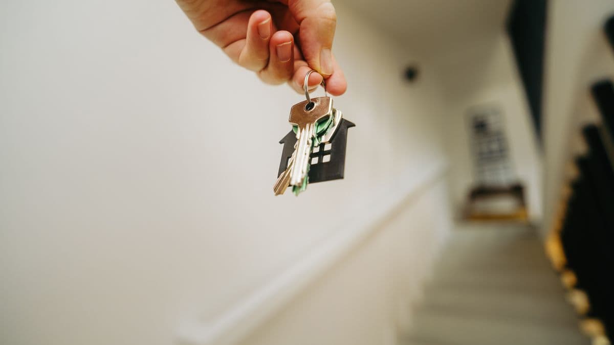 Una mano sostiene un llavero en forma de casa