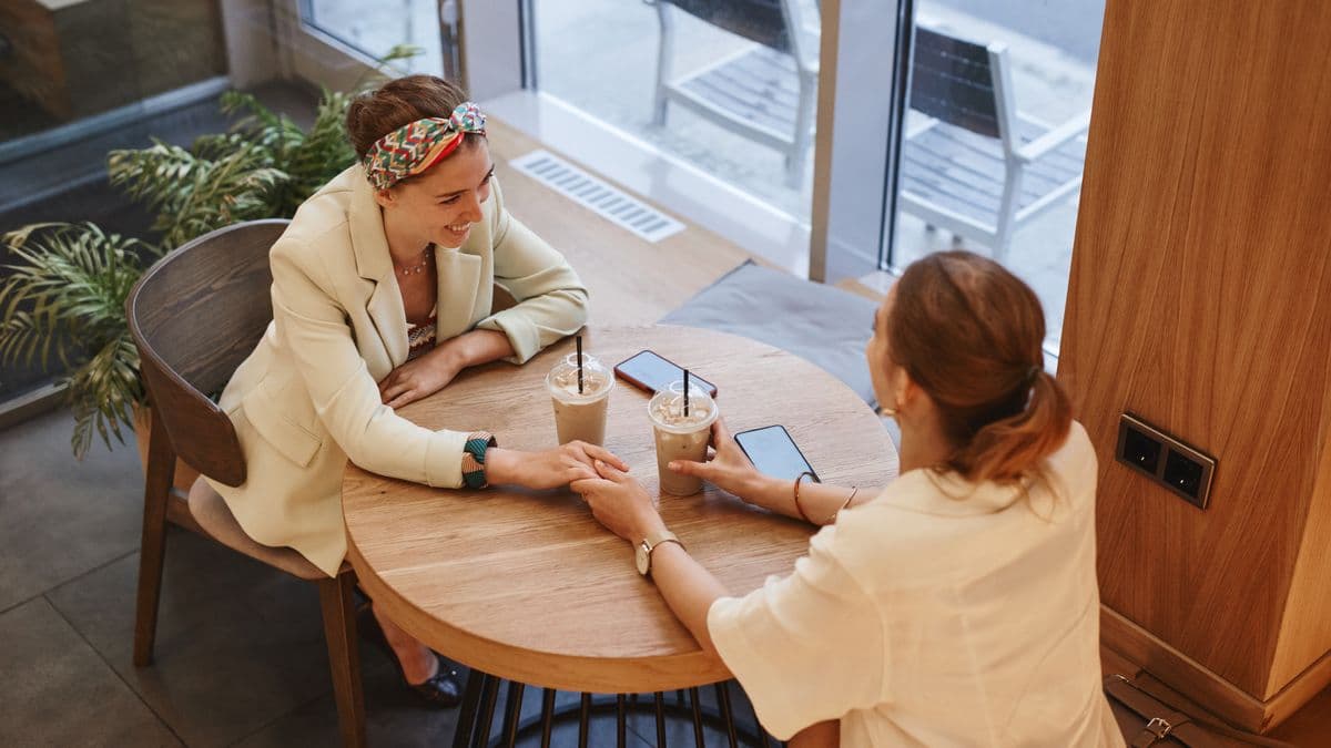 Dos mujeres platican en la mesa de un café
