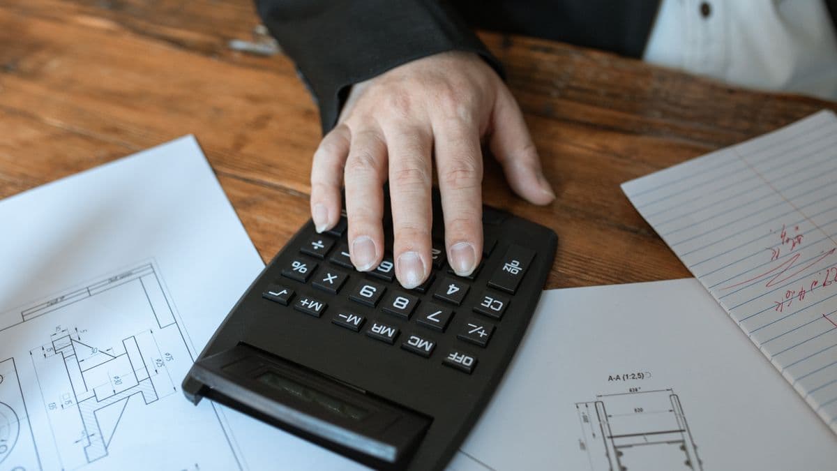 Una mano usa una calculadora sobre planos impresos