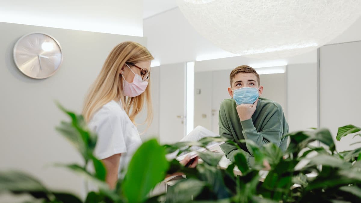Dos personas del personal de una clínica detrás de una planta en recepción