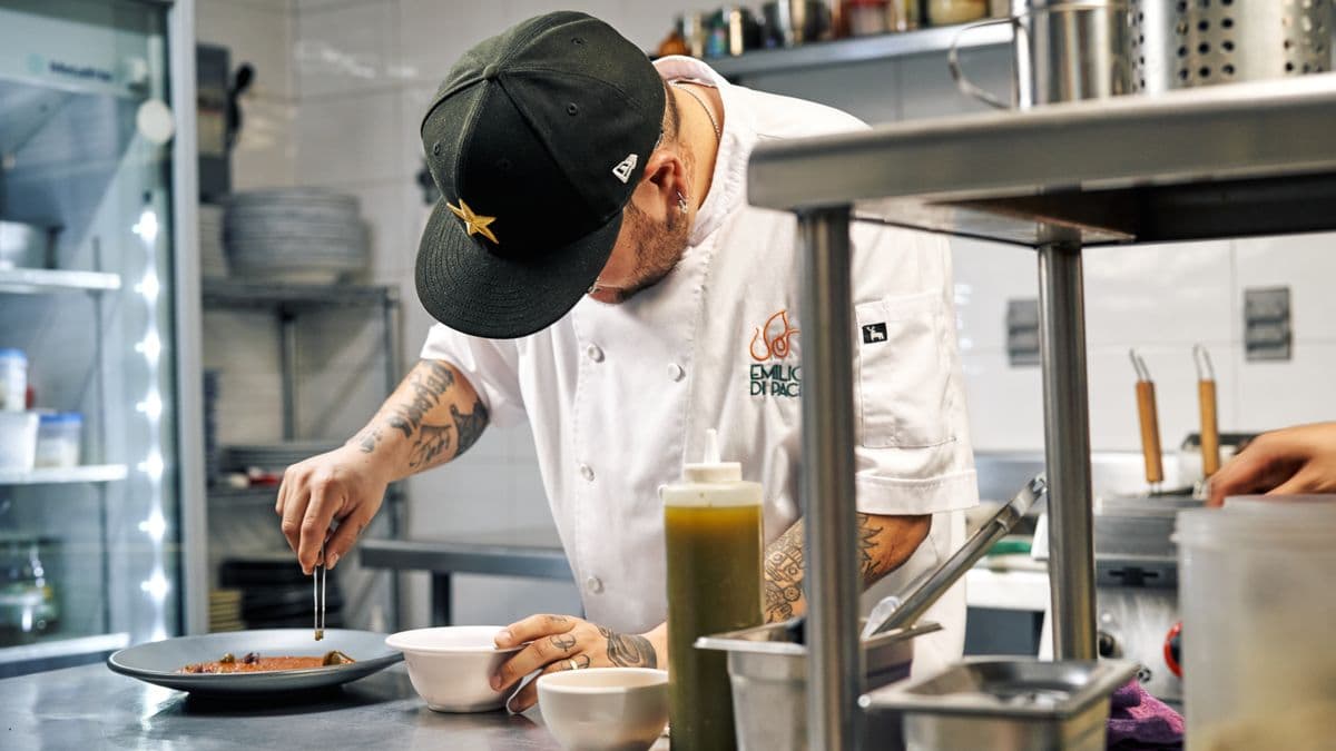 Un cocinero emplata un platillo en una cocina profesional